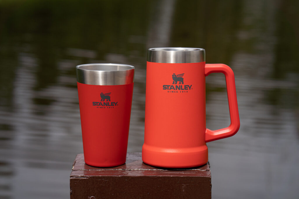 A imagem mostra um copo e uma caneca de cerveja da marca Stanley.